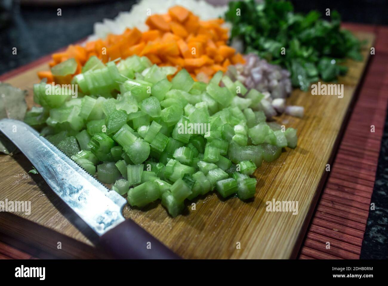 Mixed vegetables with brunoise cut for sautéing on a wooden cutting board (carrots, celery, onion and shallot) Stock Photo