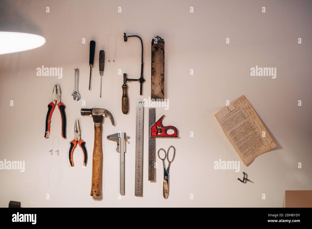 Various work tools hanging on wall at workshop Stock Photo