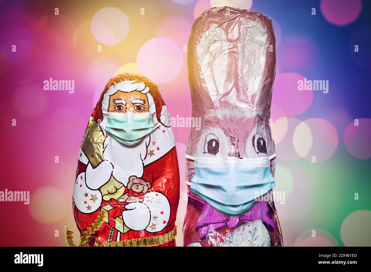 FOTOMONTAGE, Schoko-Weihnachtsmann und Schoko-Osterhase mit Schutzmaske, Weihnachtsfest zu Corona-Zeiten und Corona-Beschränkungen Stock Photo