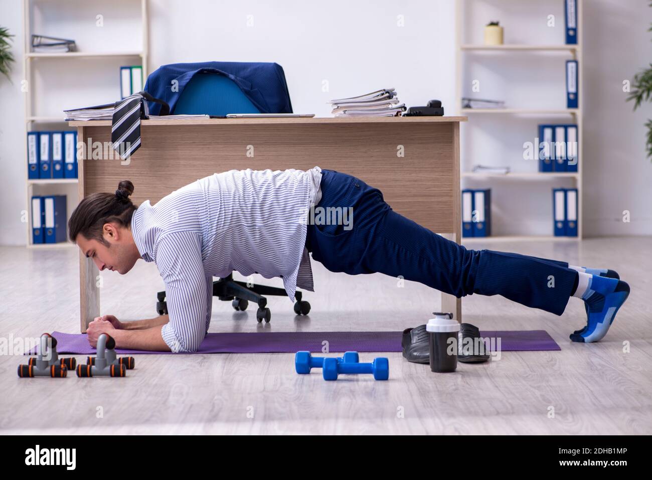 Young handsome male employee doing exercises in the office Stock Photo