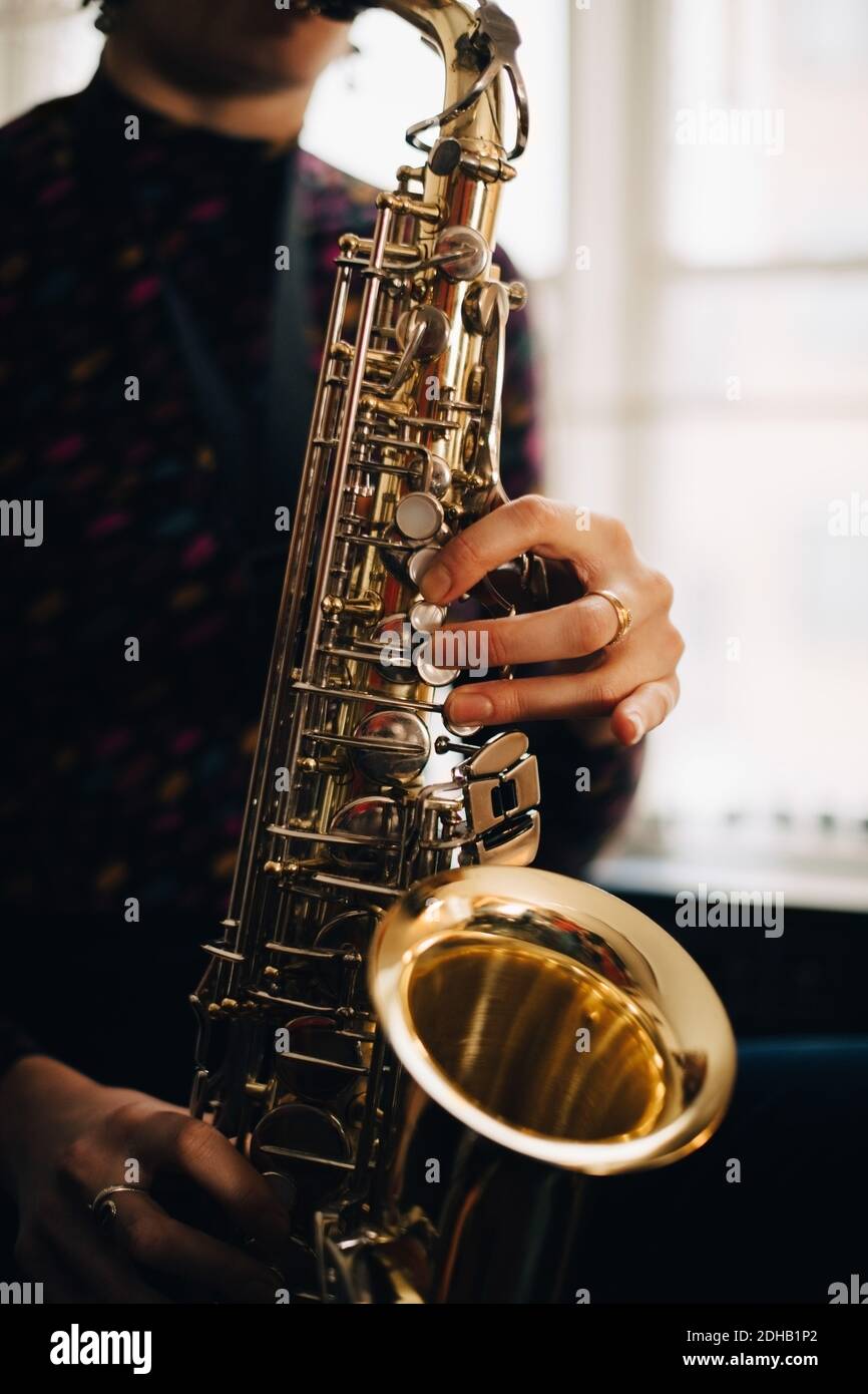 Midsection of woman playing saxophone at studio Stock Photo