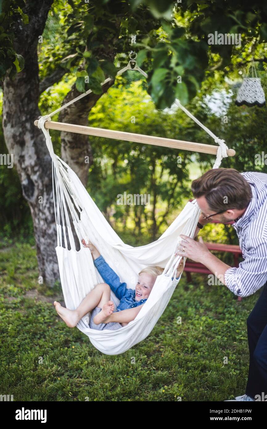 Playful father swinging cheerful son in yard Stock Photo