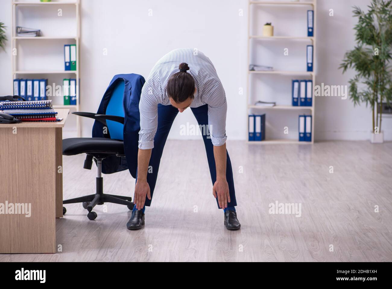 Young handsome male employee doing exercises in the office Stock Photo