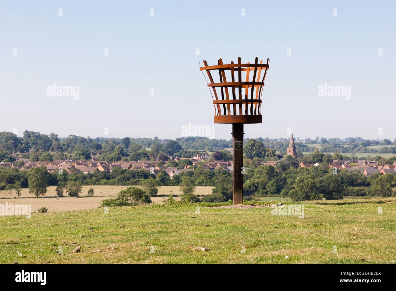 Crick, Northamptonshire - 25/06/20: A metal fire beacon on a hill above the village of Crick and the spire of St. Margaret's church. Stock Photo