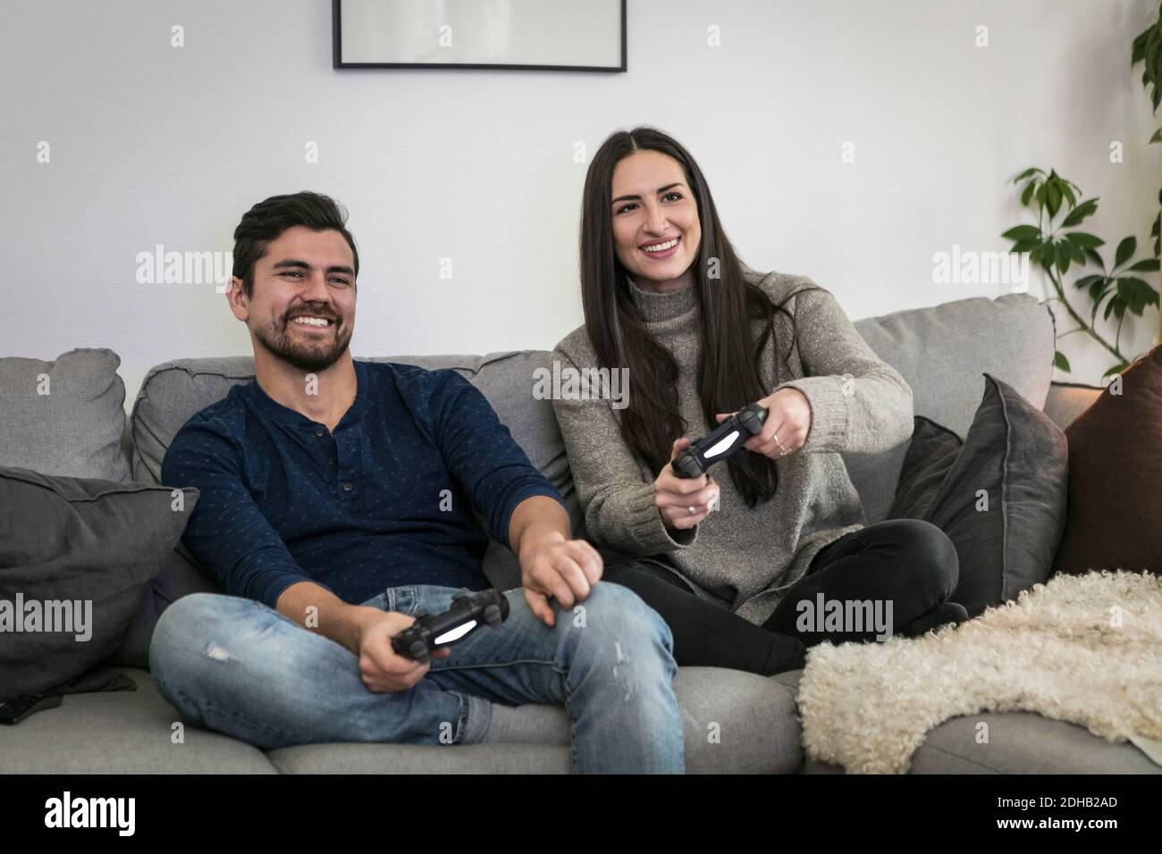 Happy Couple Sitting On The Sofa Playing Video Games Using