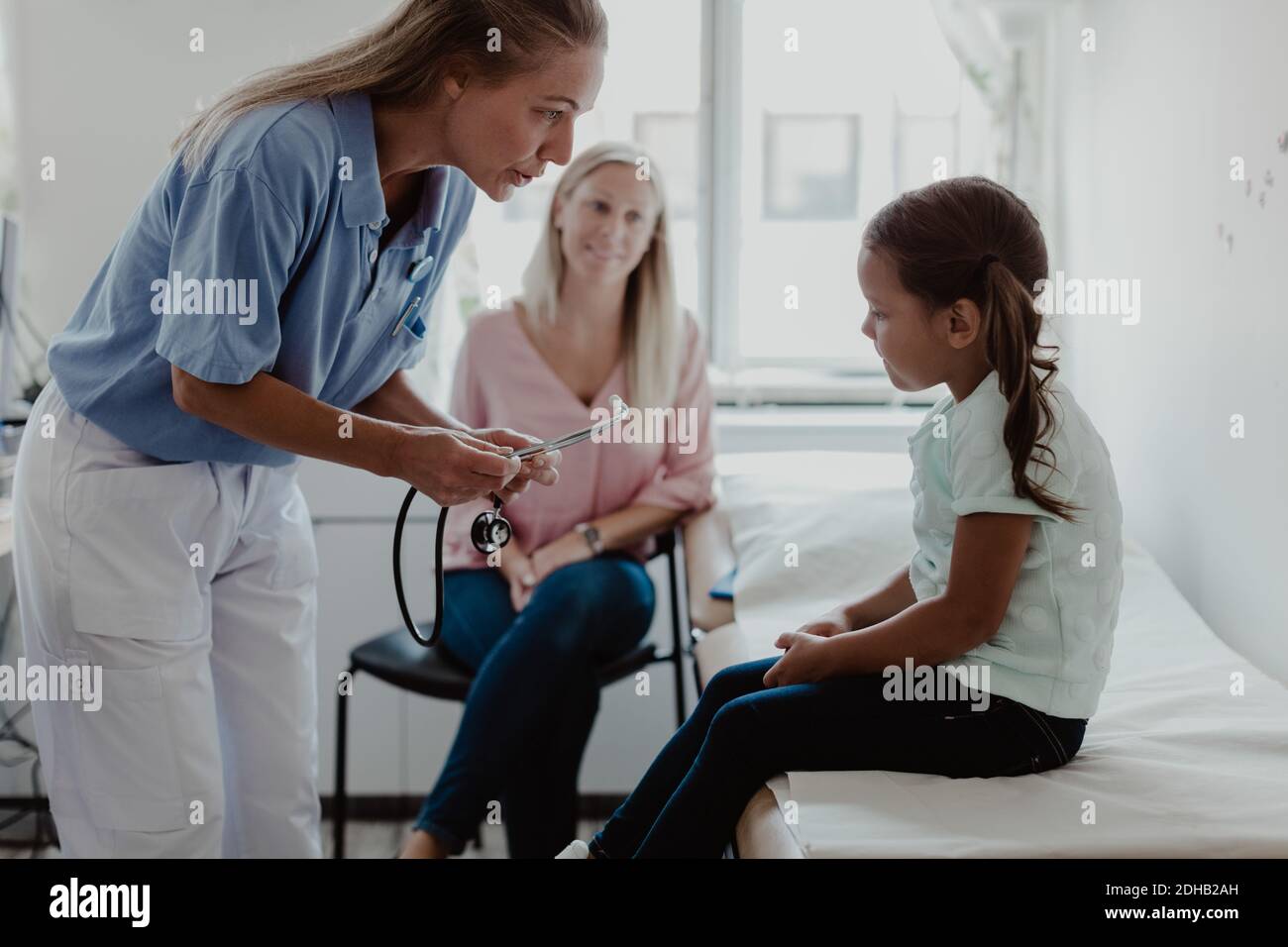 Female nurse talking with girl sitting on examination table in hospital  Stock Photo - Alamy