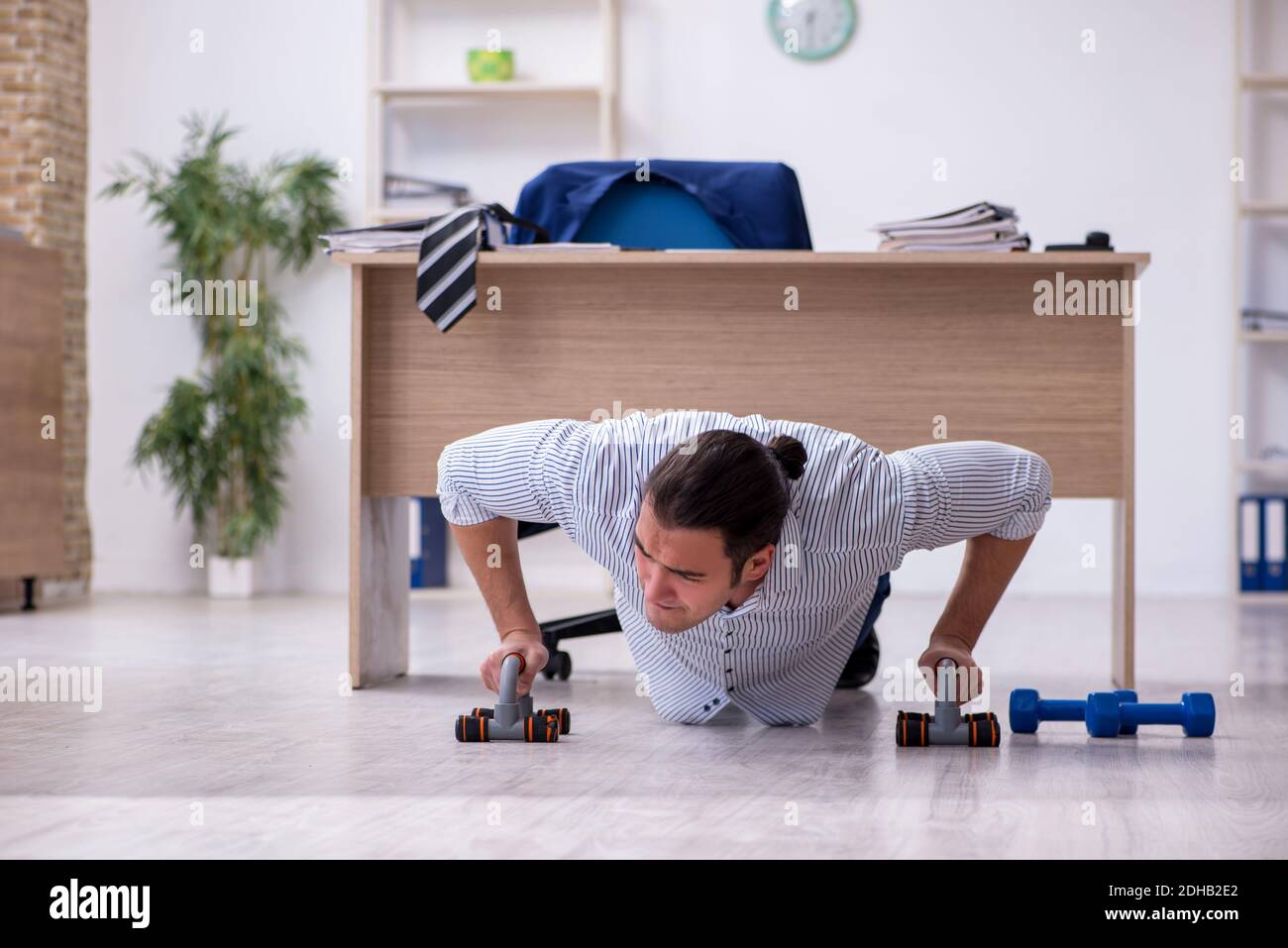 Young handsome male employee doing exercises in the office Stock Photo