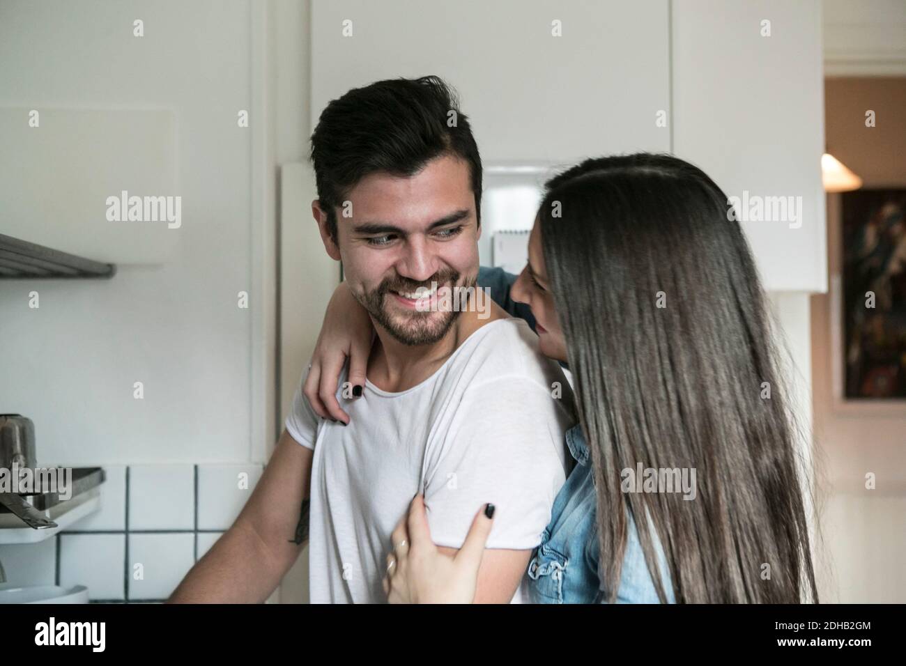 Smiling couple looking at each other while standing in kitchen Stock Photo