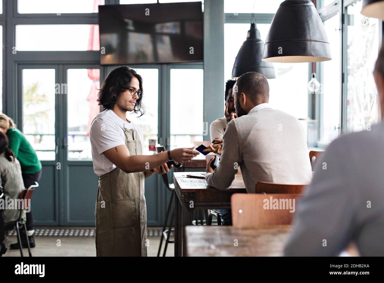 Customer giving credit card to young waiter at restaurant Stock Photo