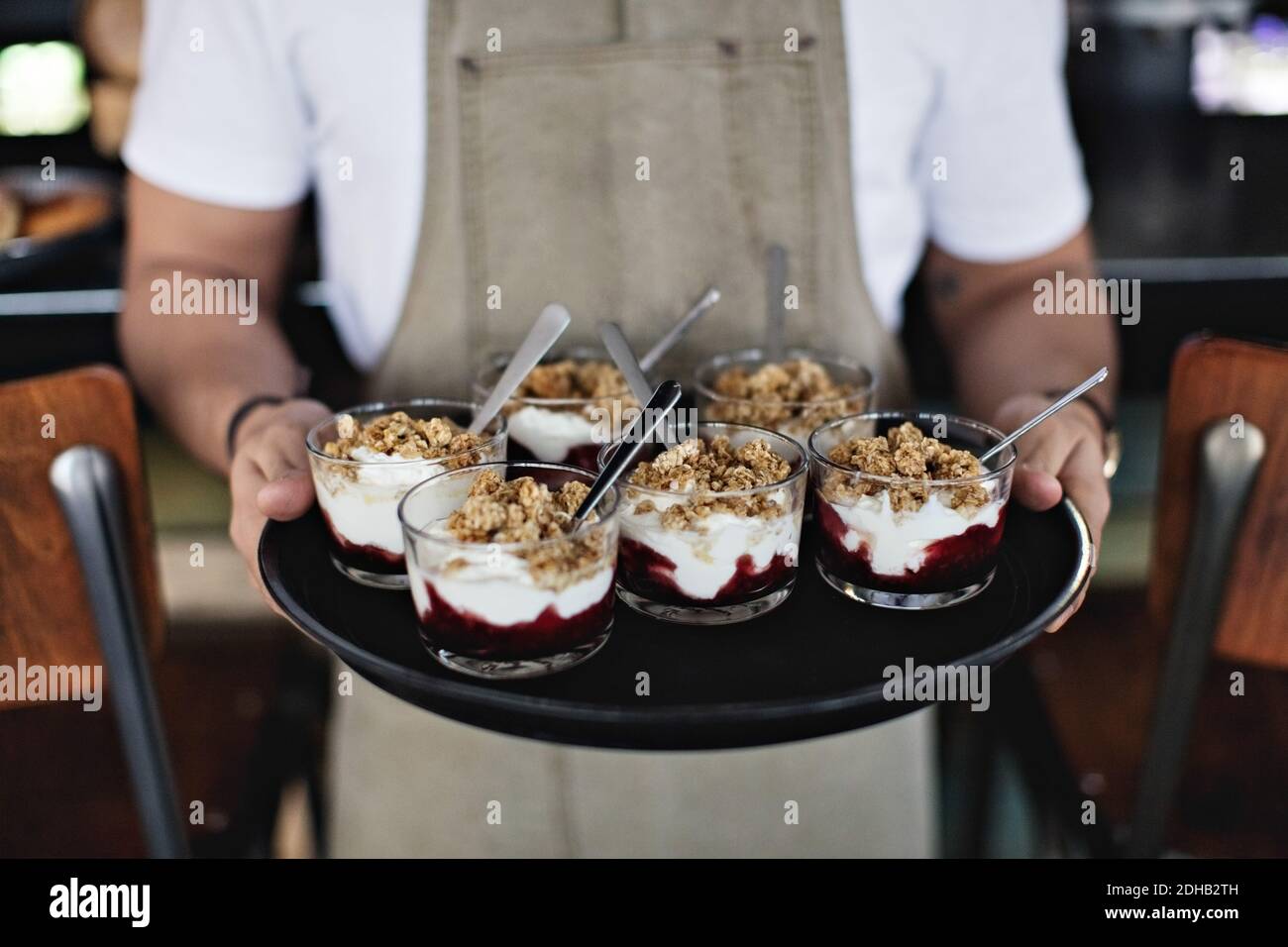 Midsection of owner holding dessert in tray while standing at counter in restaurant Stock Photo
