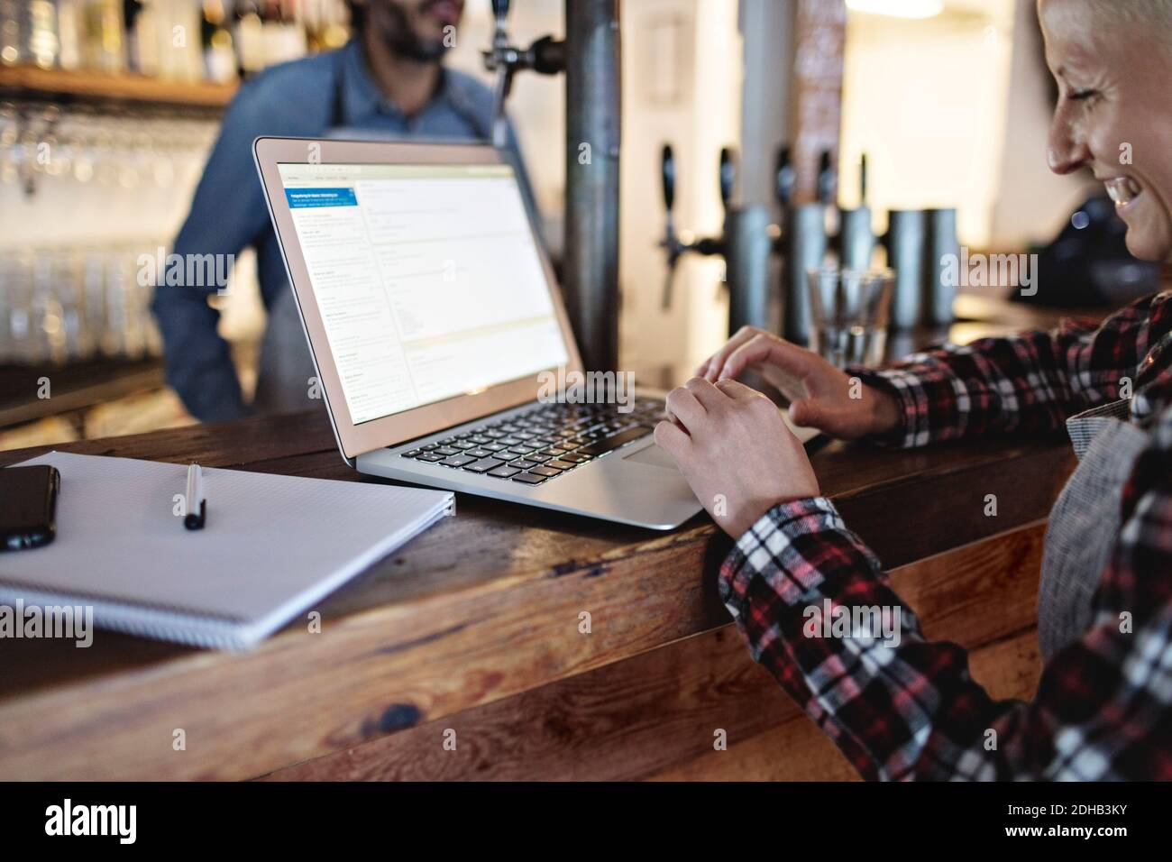 Smiling manager using laptop at bar counter Stock Photo