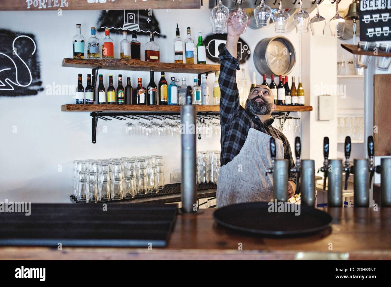 Bartender arranging wineglasses while standing at bar counter Stock Photo