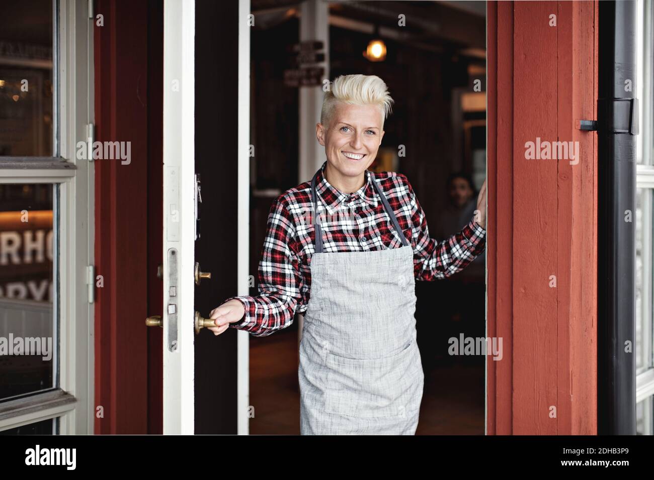 Portrait of smiling confident manual worker standing at doorway by restaurant Stock Photo