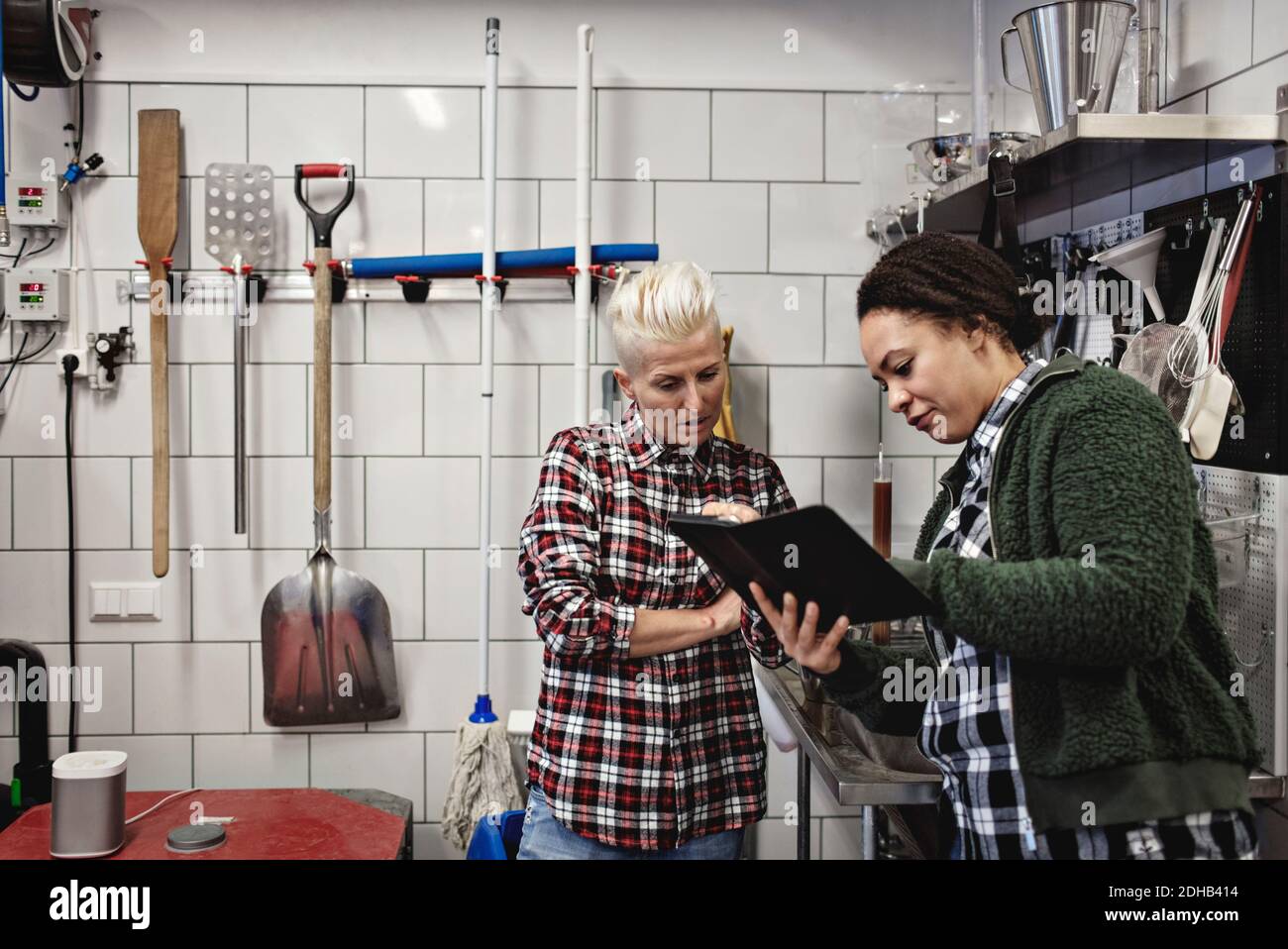 Female workers discussing over digital tablet while working in brewery Stock Photo