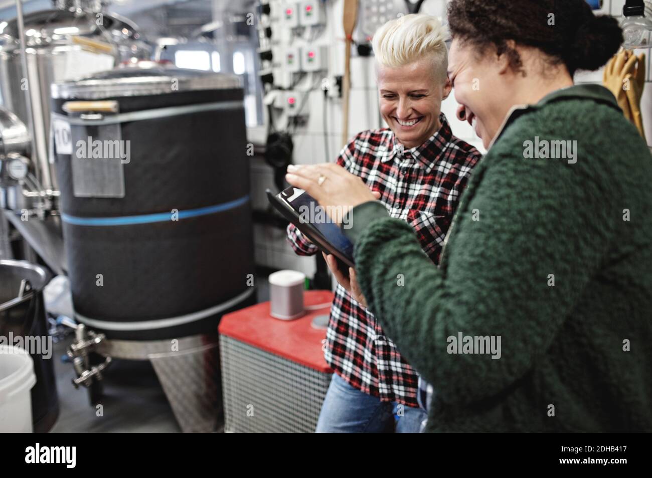 Smiling female workers discussing over digital tablet while working in brewery Stock Photo