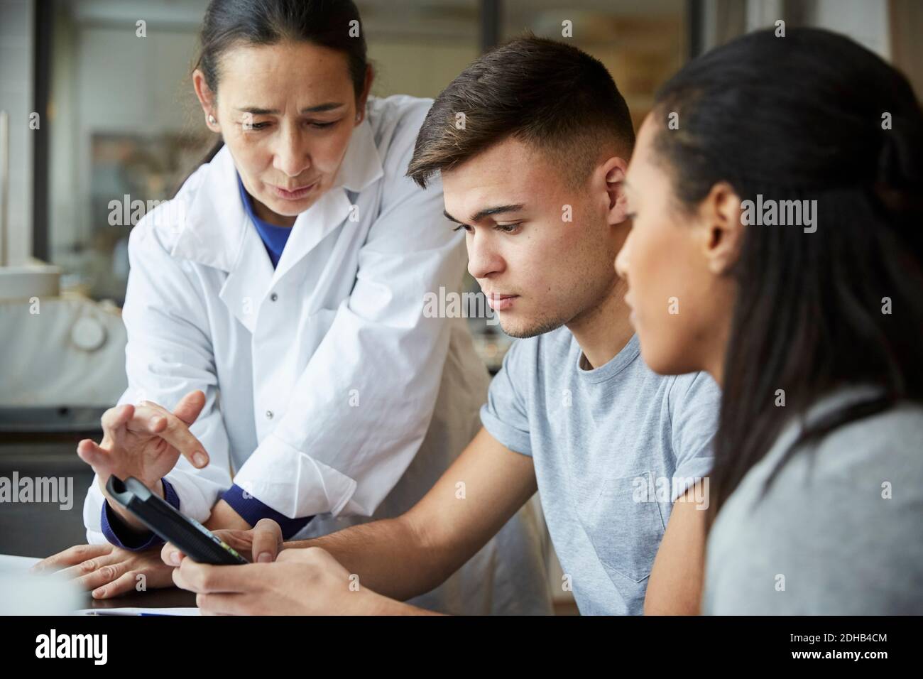 Mature teacher with young students using calculator in engineering classroom Stock Photo
