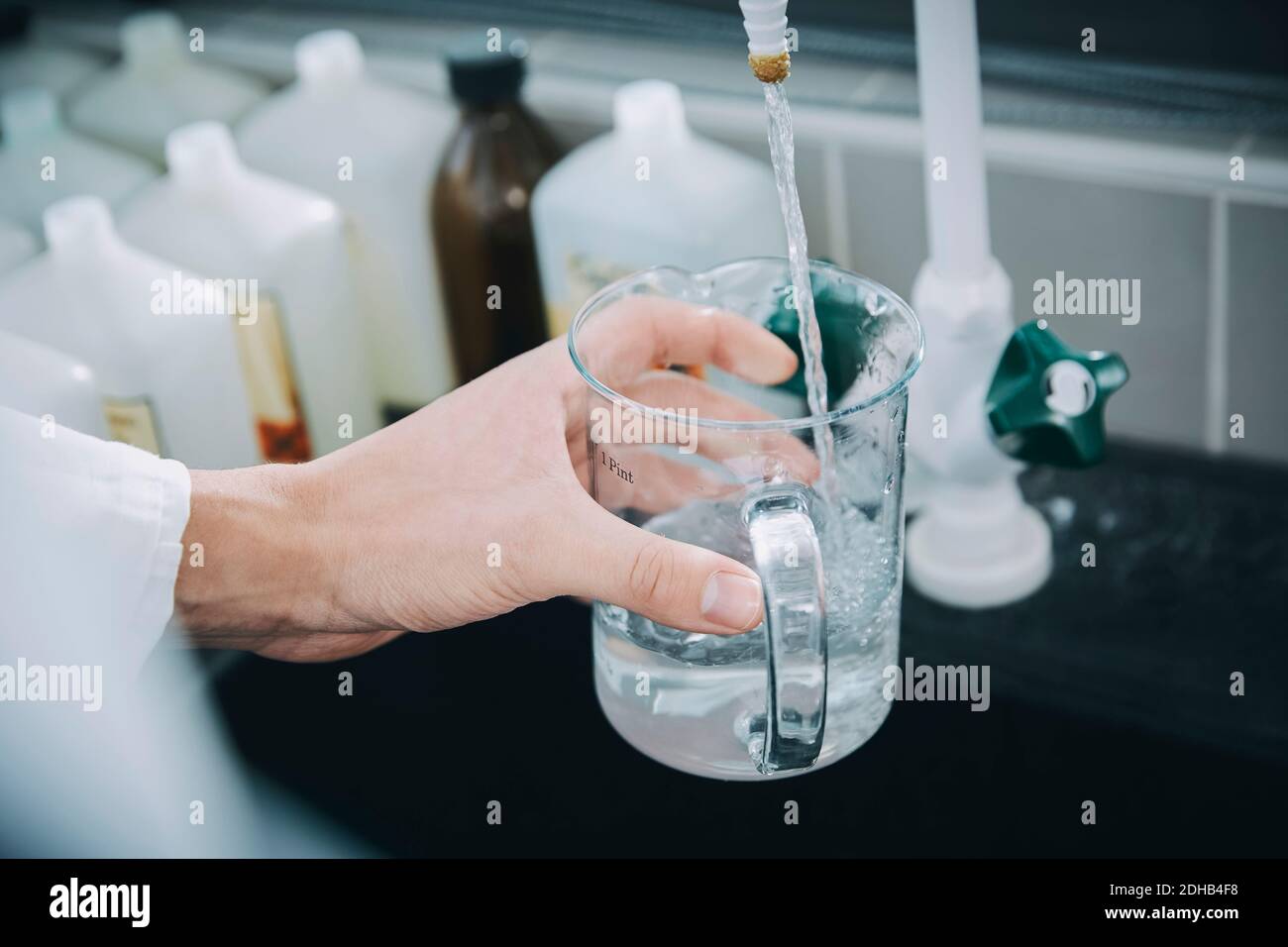 Cropped hand of female student filling beaker with liquid solution in chemistry laboratory Stock Photo
