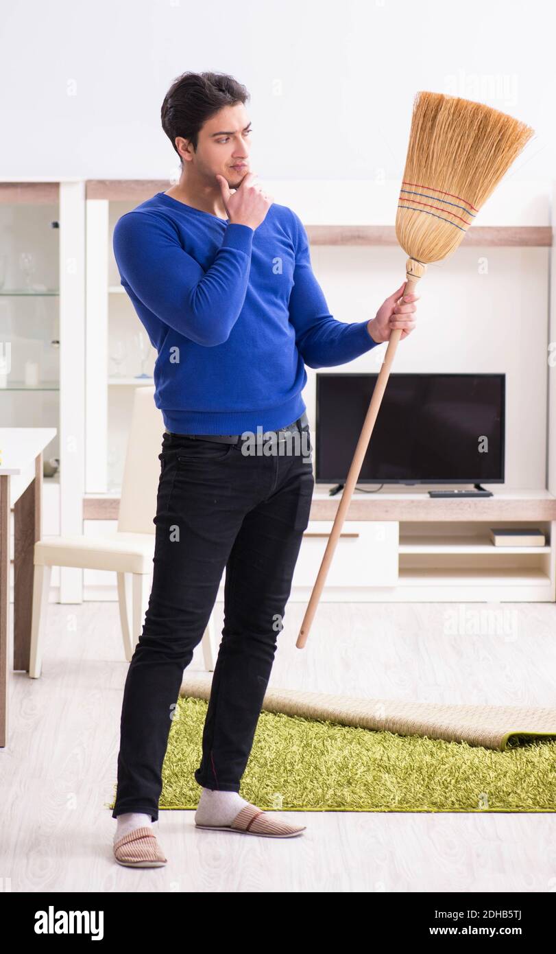 Young man cleaning floor with broom Stock Photo Alamy