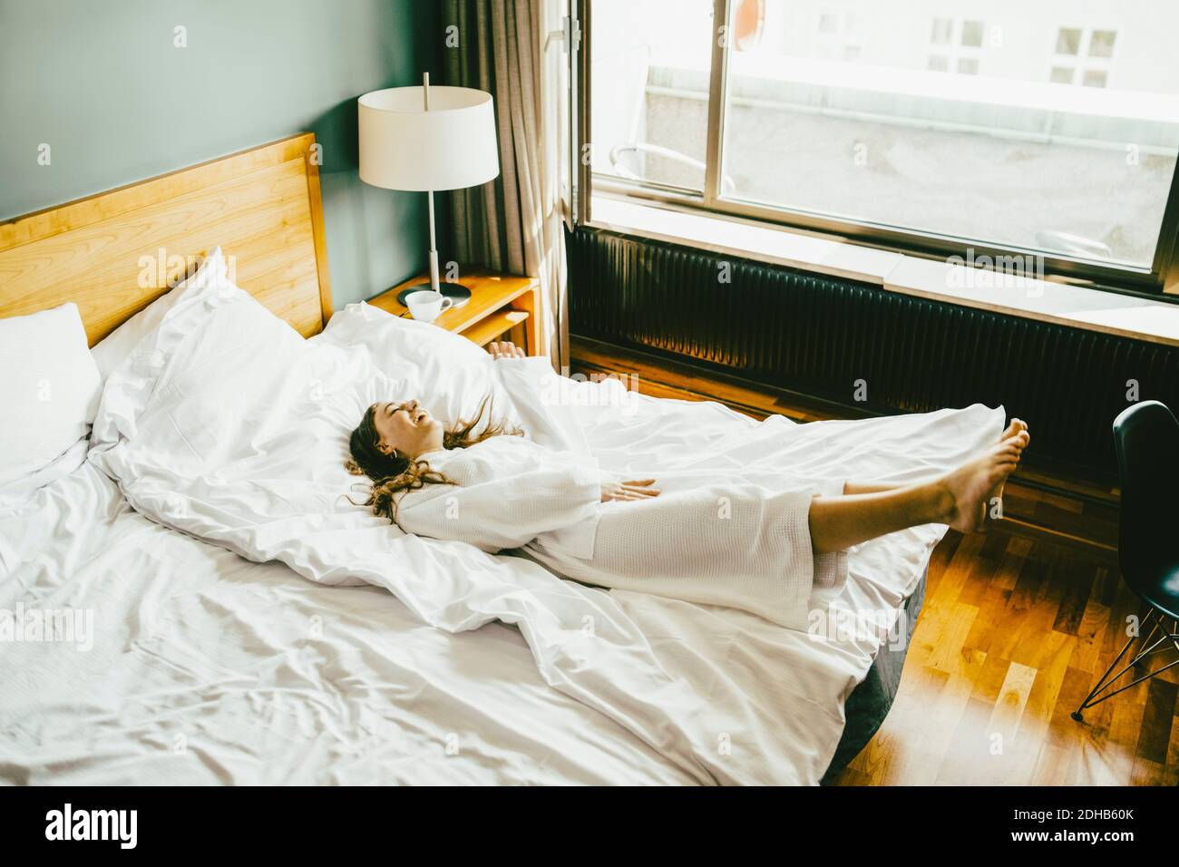 Smiling woman in bathrobe having fun on bed at hotel room Stock Photo