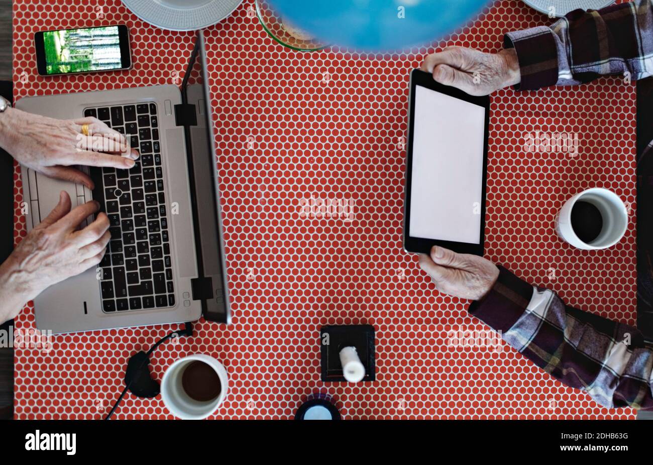 Directly above view of retired couple using technologies at dining table Stock Photo