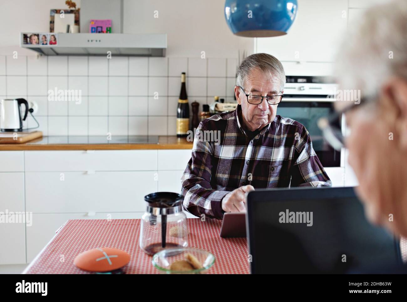 Senior couple using technologies sitting at dining table Stock Photo