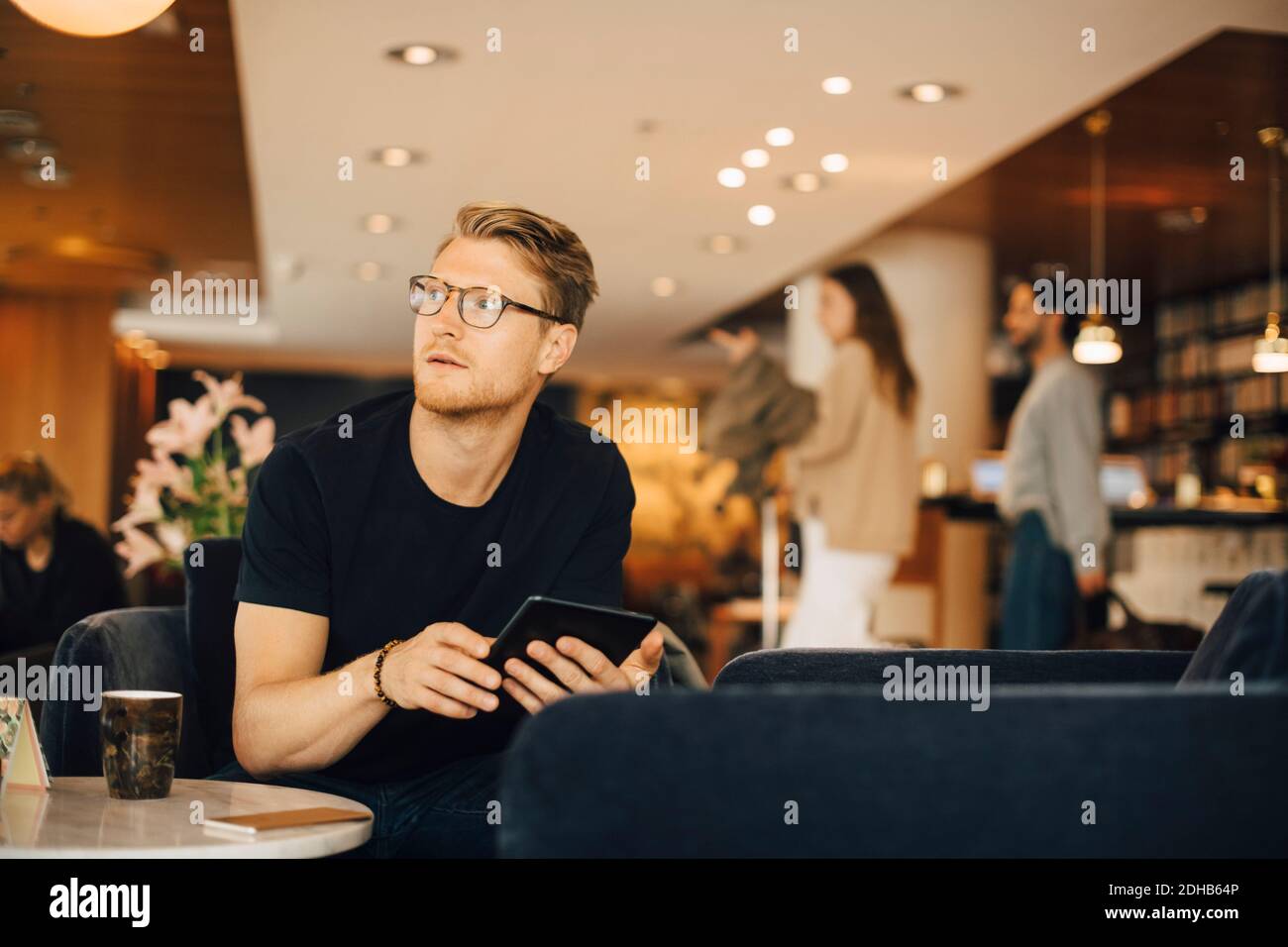 Thoughtful man looking away while using digital tablet in restaurant Stock Photo