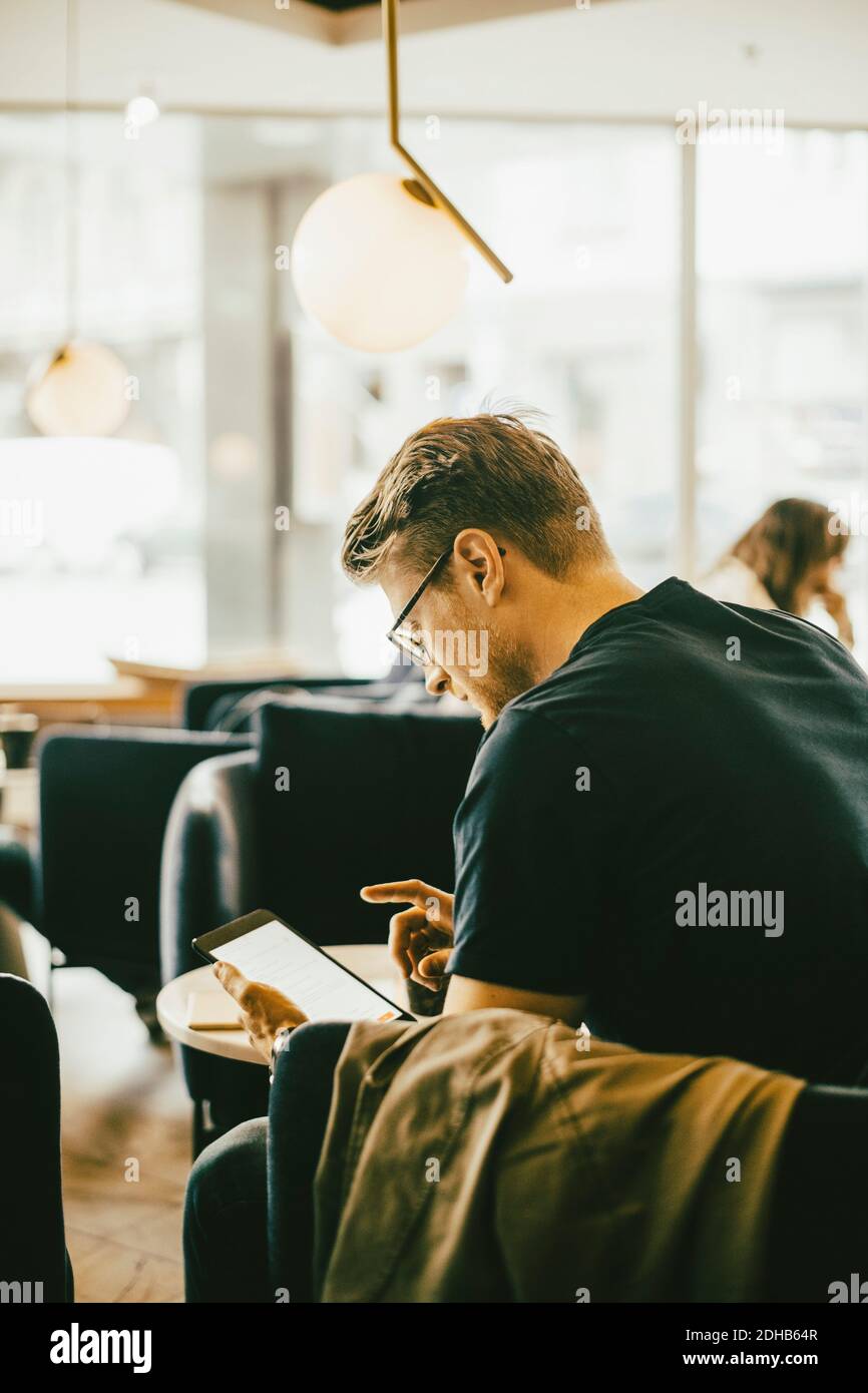 Side view of man using digital tablet while sitting in restaurant Stock Photo