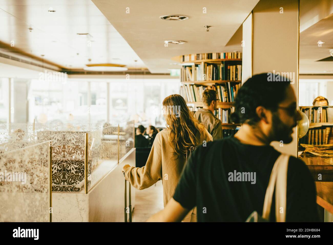 Rear view of people walking with luggage in hotel lobby Stock Photo