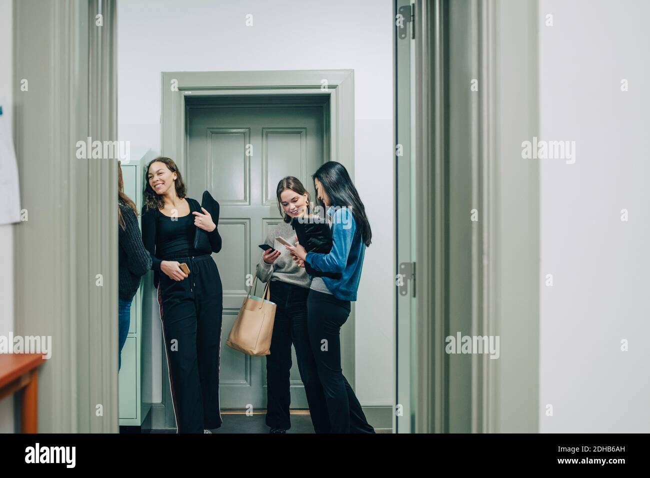 Cheerful female high school students in corridor at school Stock Photo ...