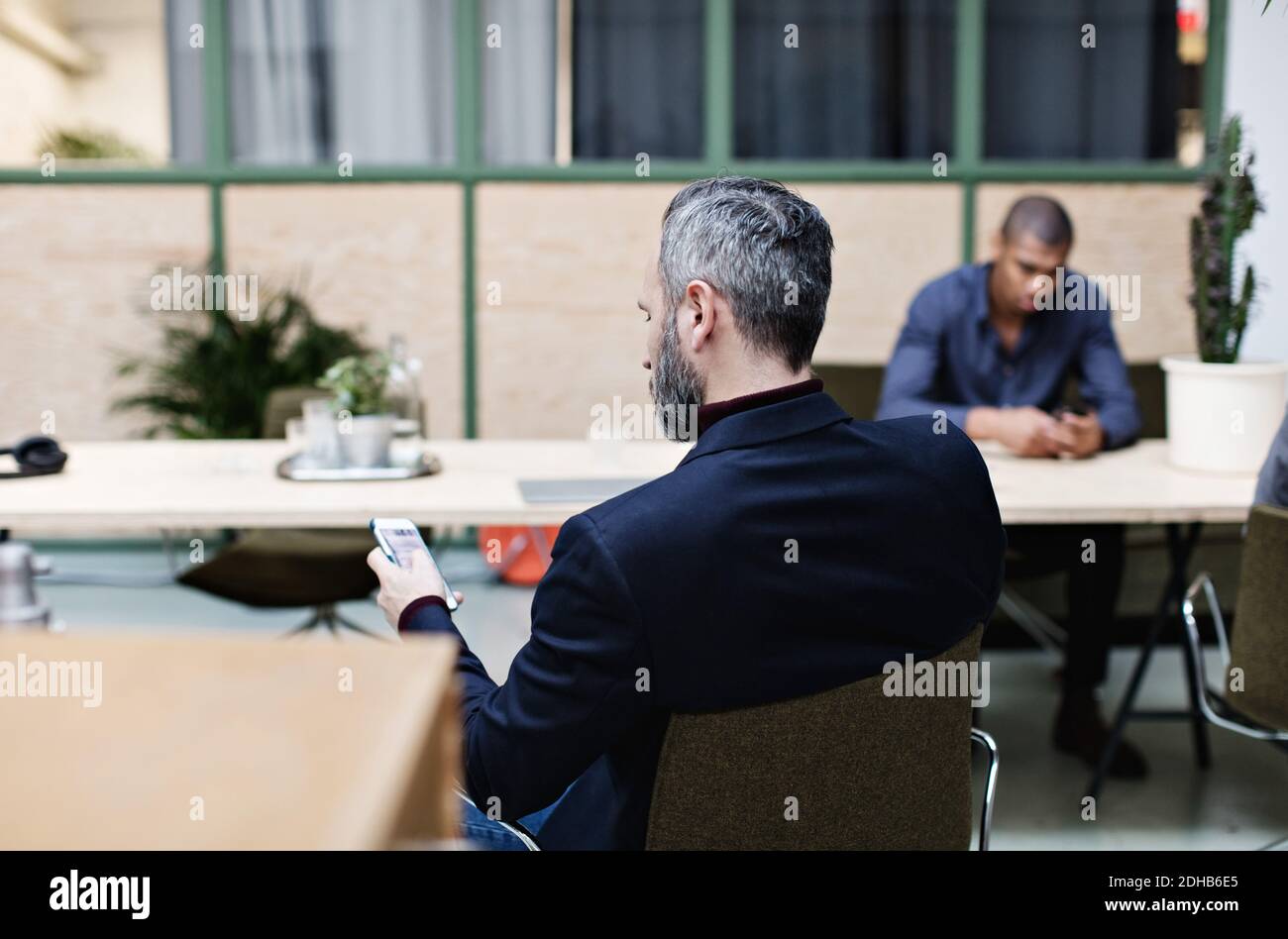Mature businessman using mobile phone while sitting at office Stock Photo