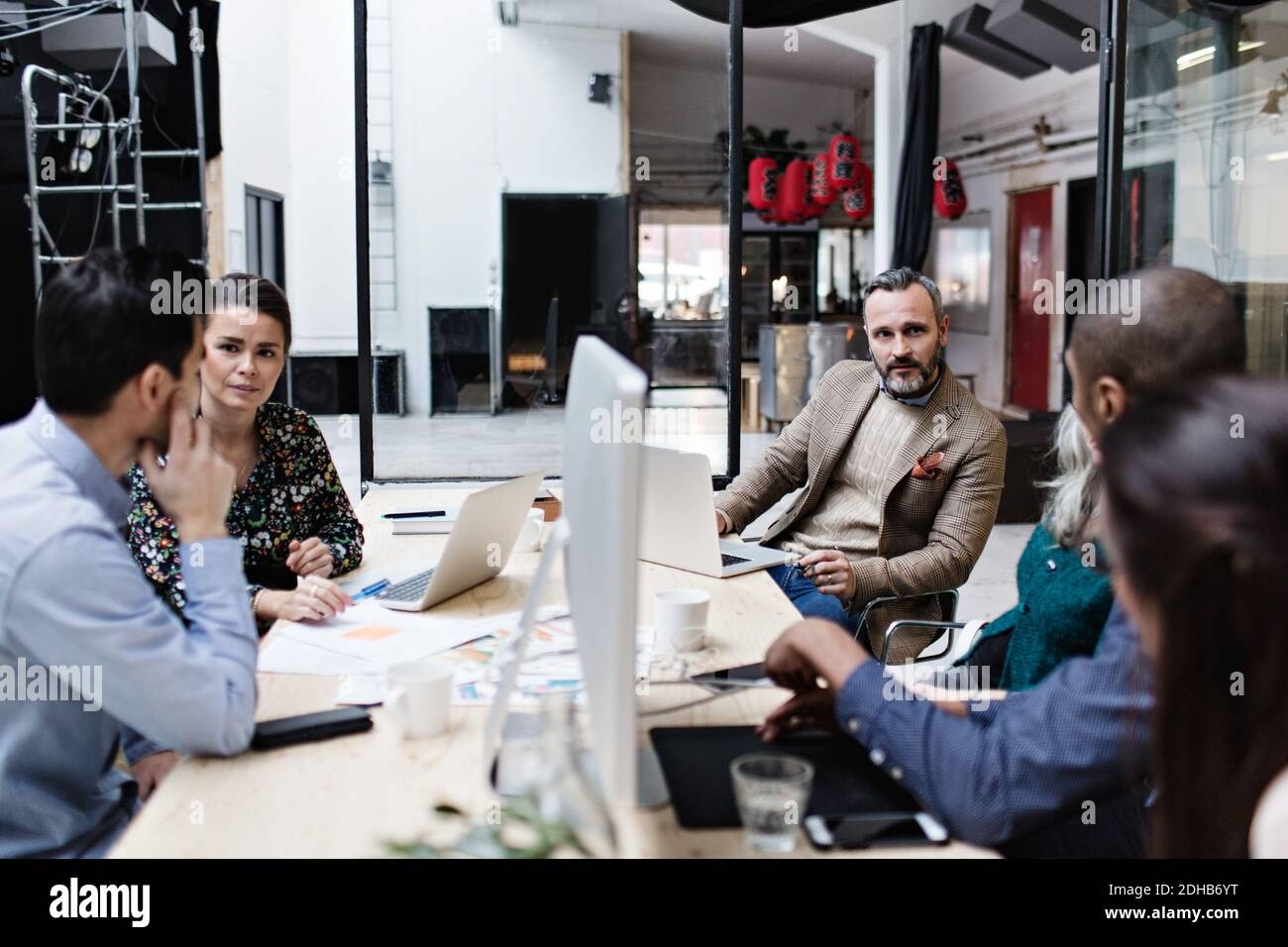 Business colleagues discussing in meeting while using technologies at creative office Stock Photo
