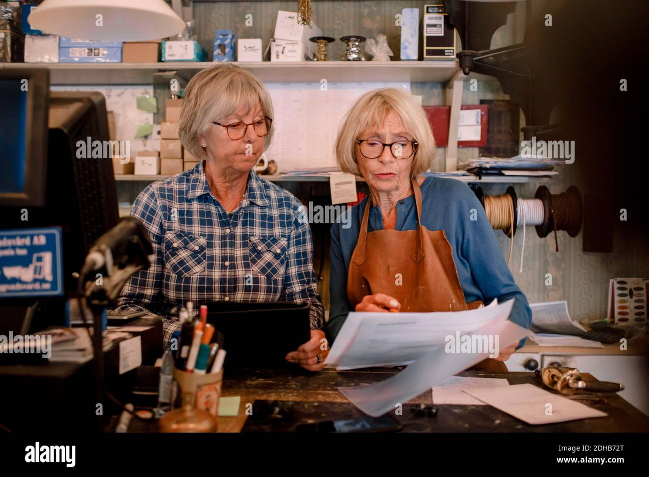 Confident senior female owners discussing over documents at checkout in hardware store Stock Photo