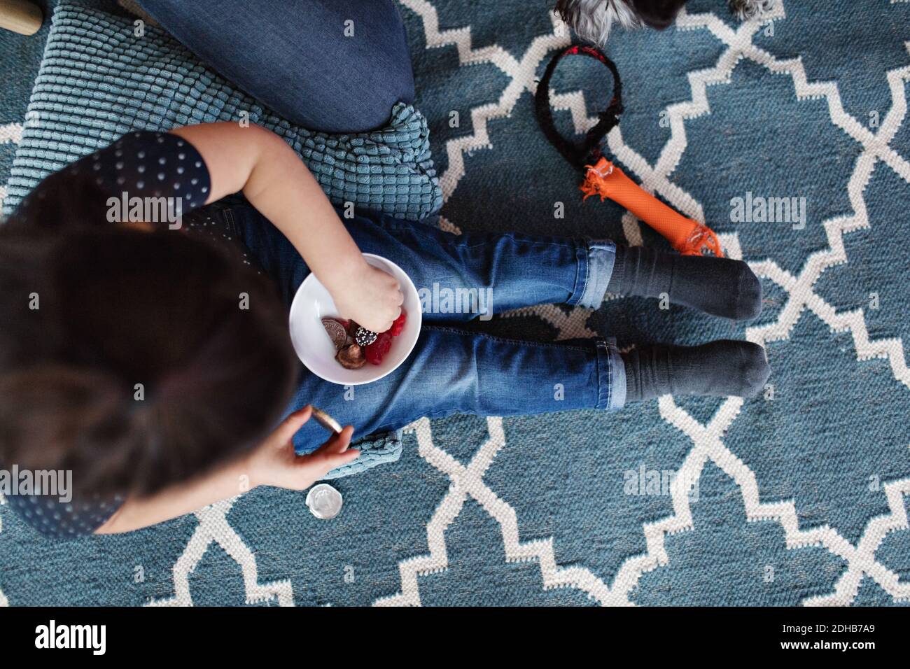 Directly above shot of girl eating candies while sitting on carpet at home Stock Photo