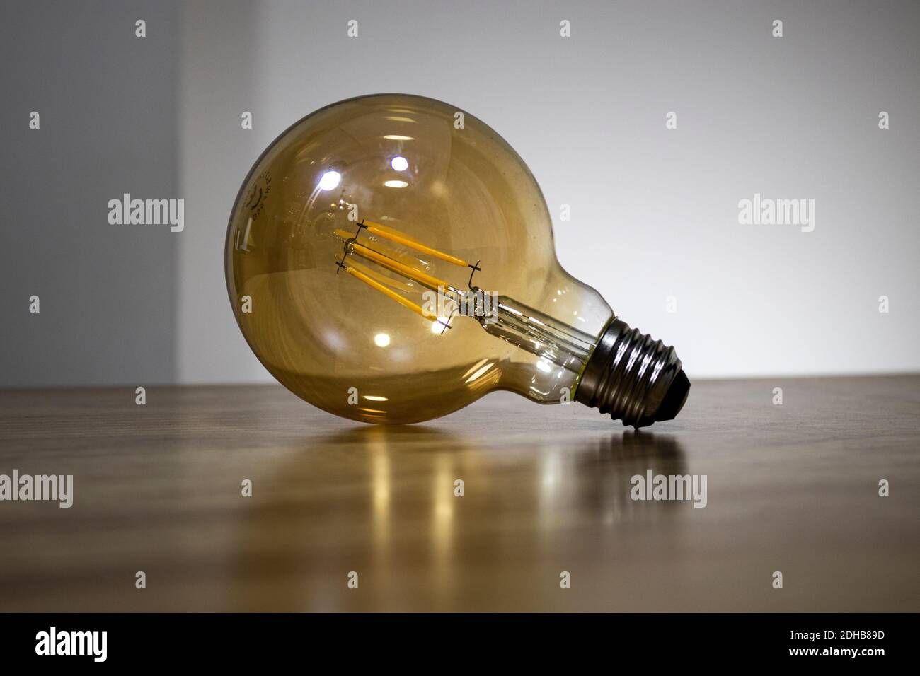 Big filament bulb with a yellow light on brown table. Large led lamps in retro style to the E27. Vintage style single lamp. Stock Photo