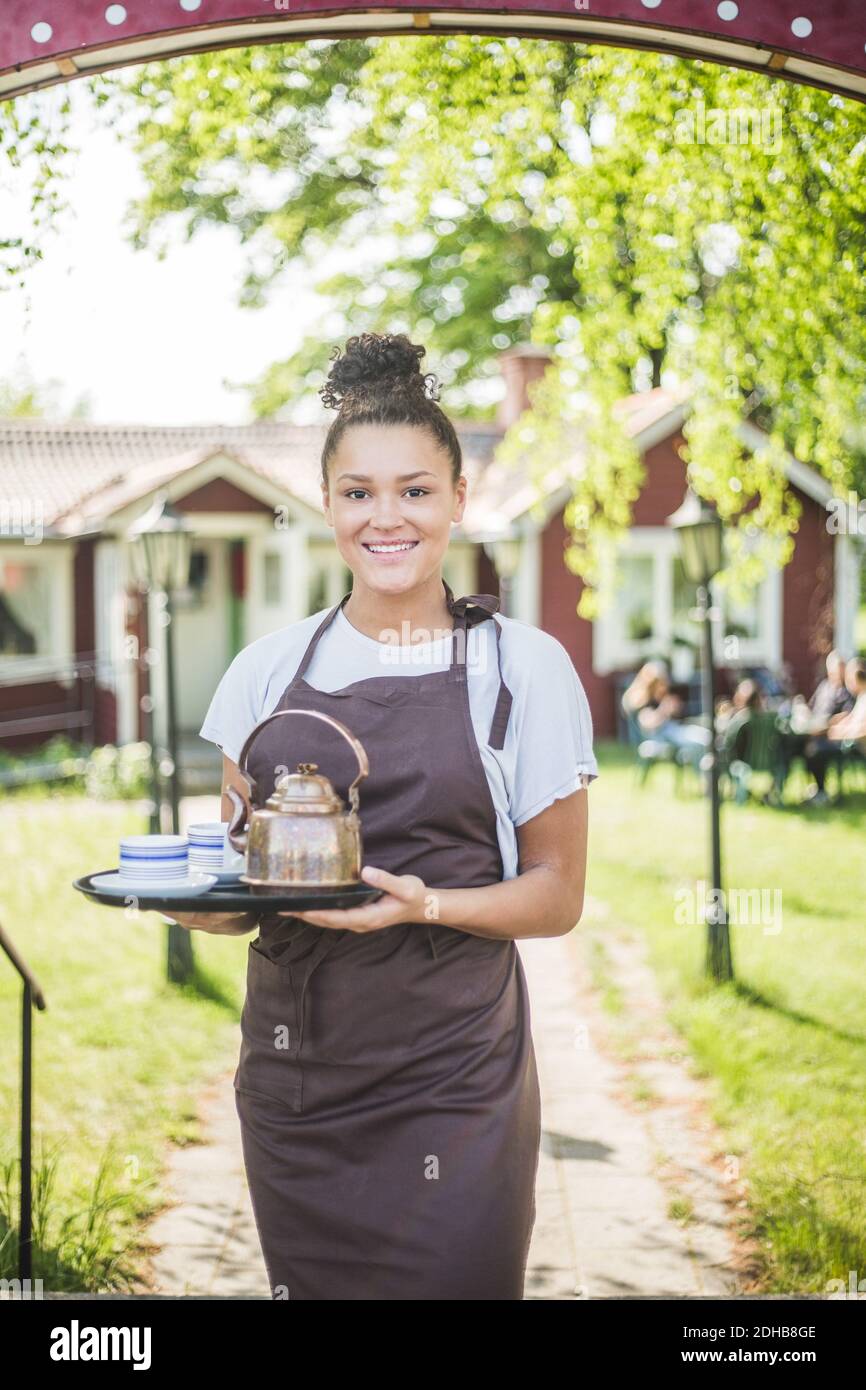 Portrait of smiling waitress holding serving tray at restaurant Stock Photo