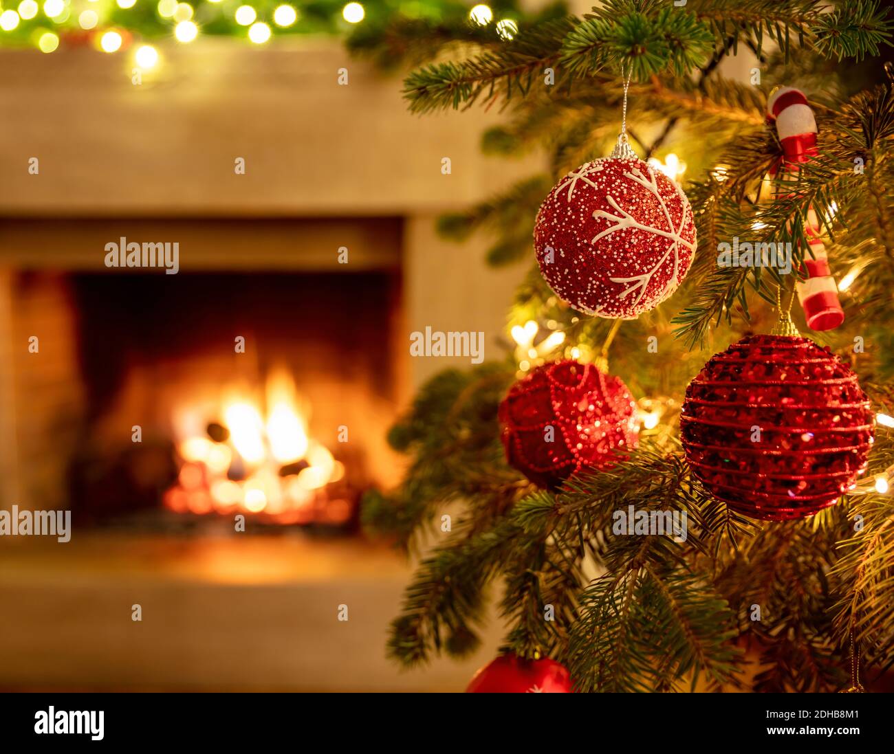 Christmas tree, burning fireplace background. Warm cozy Xmas holiday home.  Christmas bauble closeup, greeting card template, banner Stock Photo - Alamy