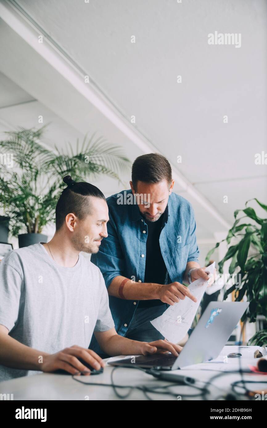 Creative businessmen discussing over document at desk in office Stock Photo