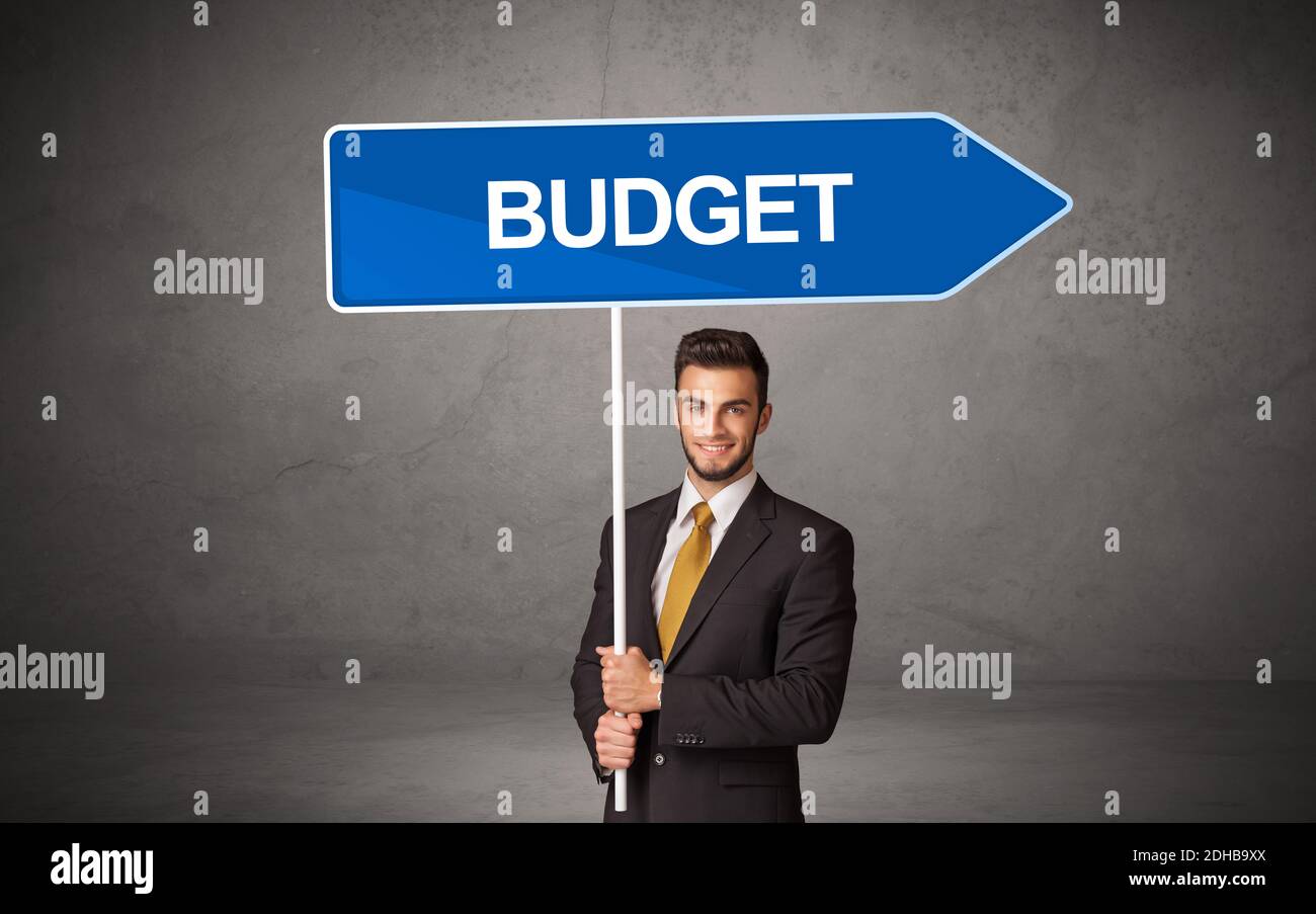 Young business person in casual holding road sign with BUDGET inscription, new business direction concept Stock Photo