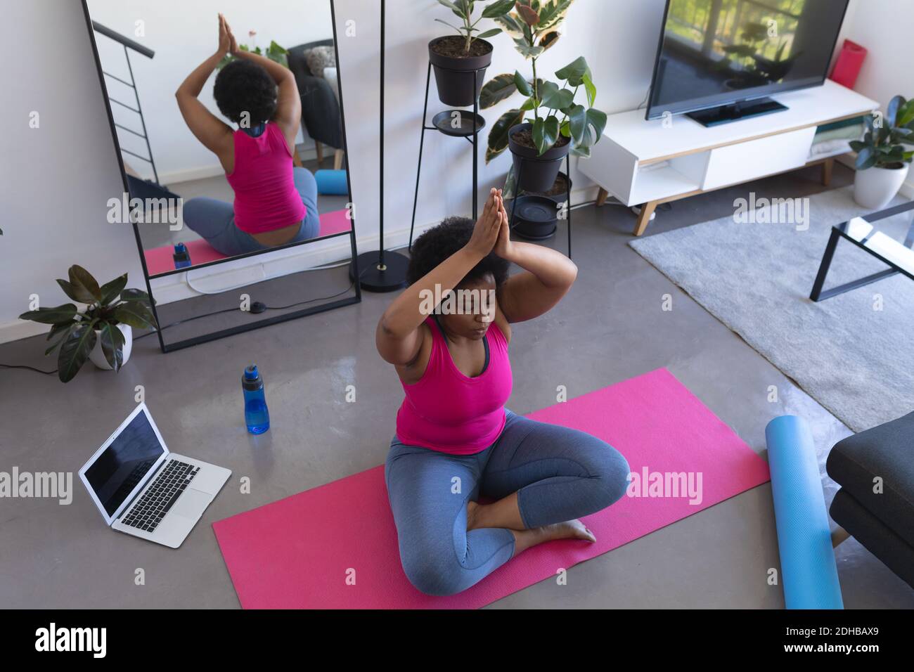 African american woman doing yoga meditation sitting on mat wearing ...