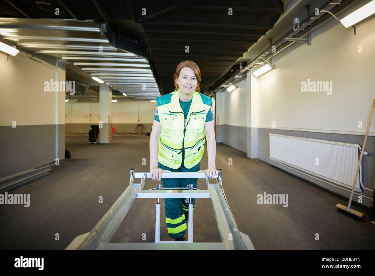 Portrait of female paramedic with stretcher in corridor at hospital Stock Photo