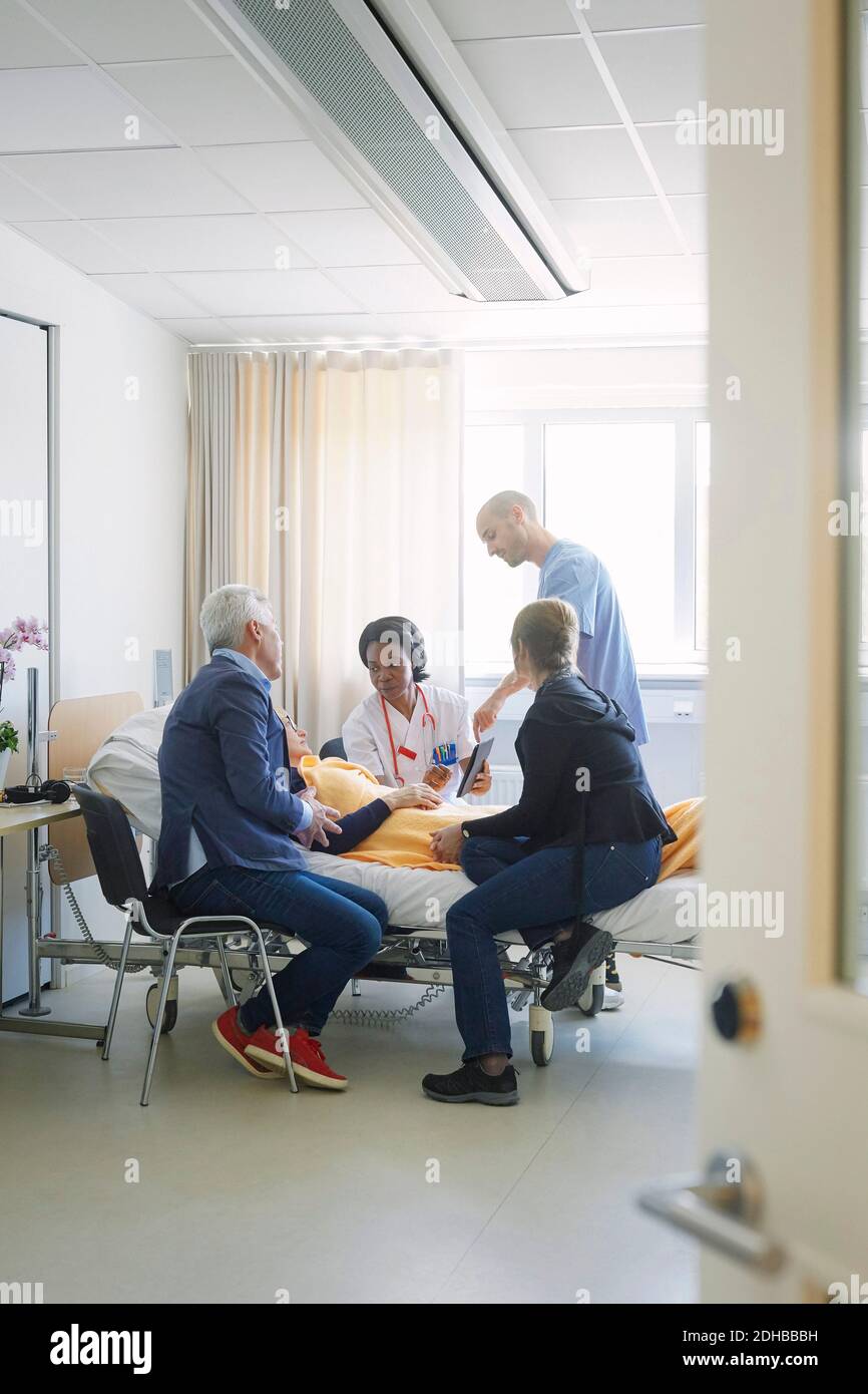 Healthcare workers discussing with patient and her friends in hospital ward Stock Photo