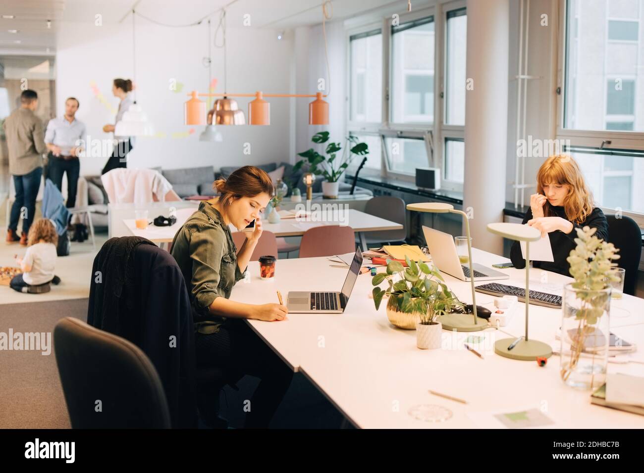 Female business colleagues working at illuminated desk in creative office Stock Photo