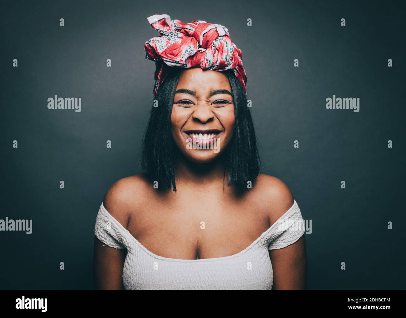 Portrait of happy woman wearing head tie over gray background Stock Photo