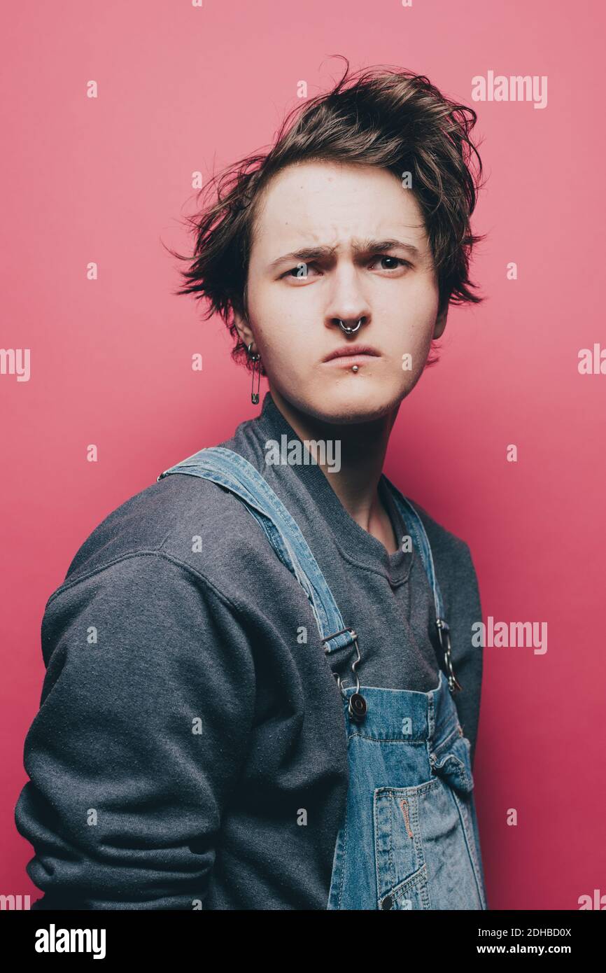 Trendy young man looking suspiciously over pink background Stock Photo