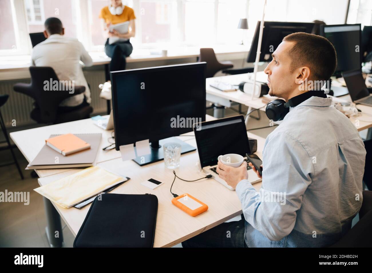 Male computer programmer looking away while sitting at desk in creative office Stock Photo