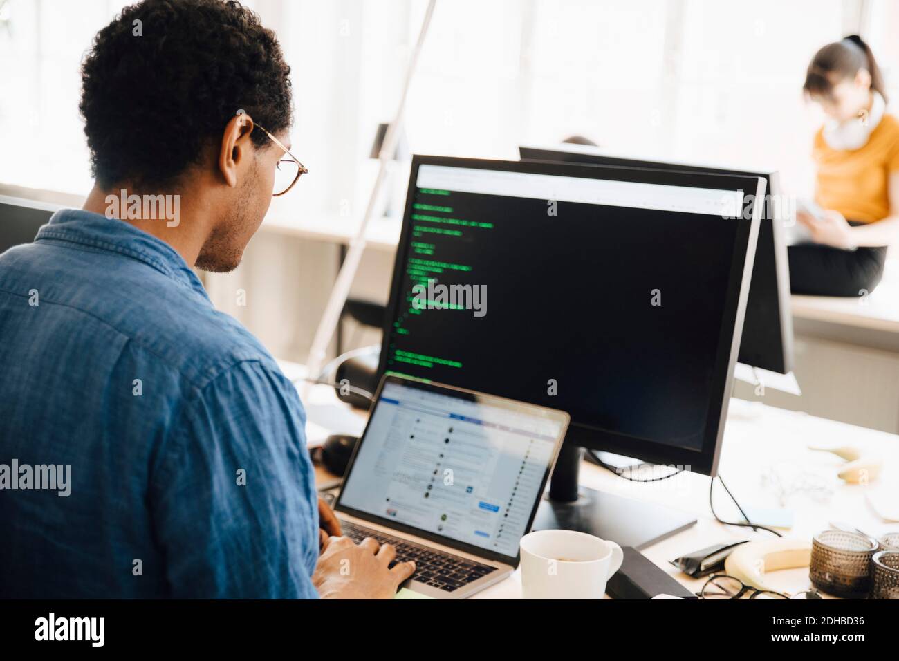 Male computer hacker using laptop on desk while sitting in creative office Stock Photo