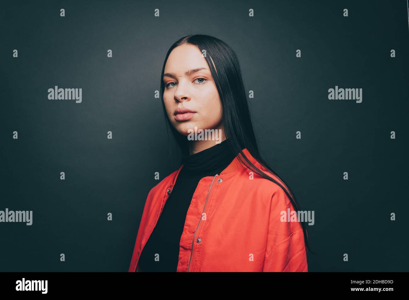 Portrait of woman wearing orange jacket over gray background Stock Photo