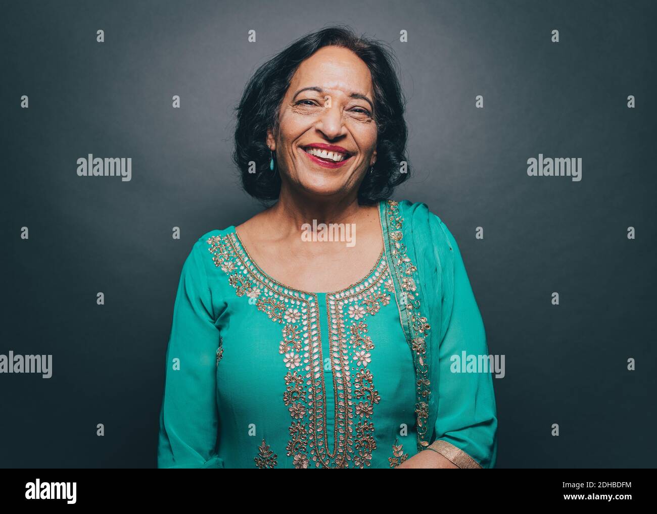 Portrait of smiling senior woman wearing salwar kameez against gray background Stock Photo