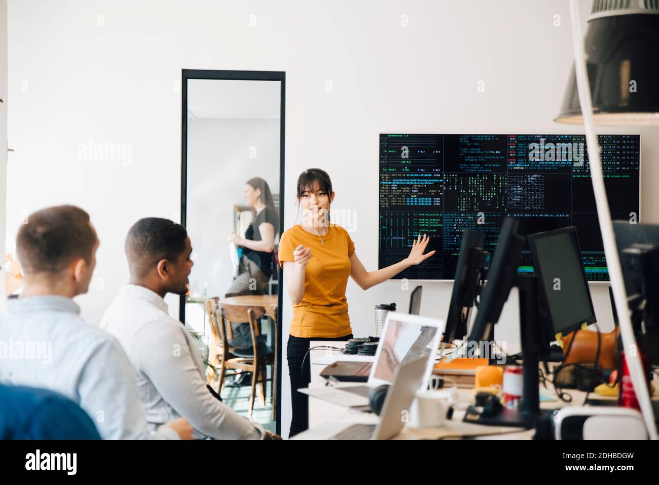 Female hacker interacting with colleagues while giving presentation in office Stock Photo