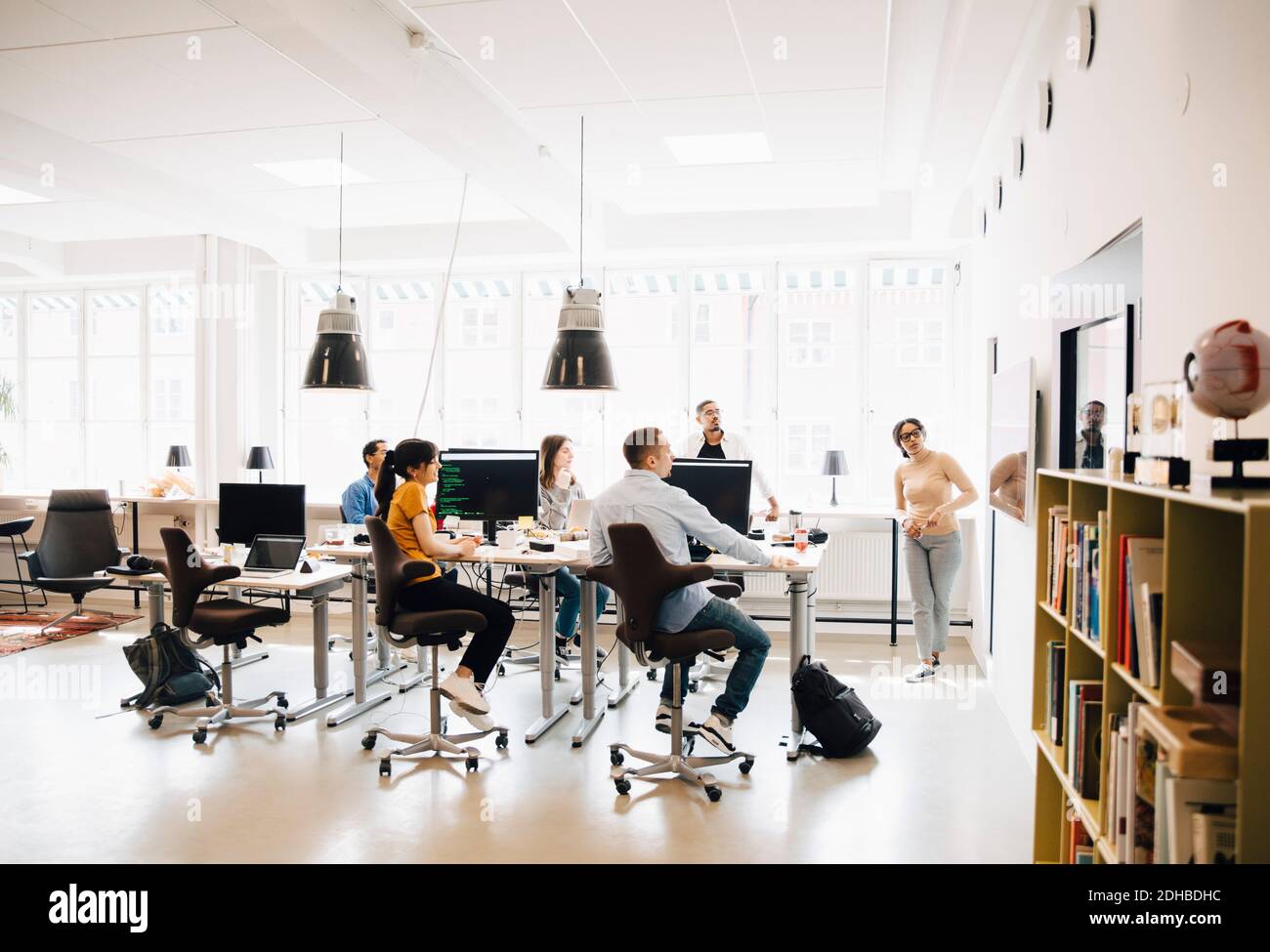 Female computer hacker giving presentation to programmers during meeting in creative office Stock Photo